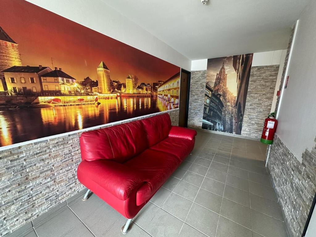 a red couch in a room with a painting at Hôtel NOROTEL in Brumath