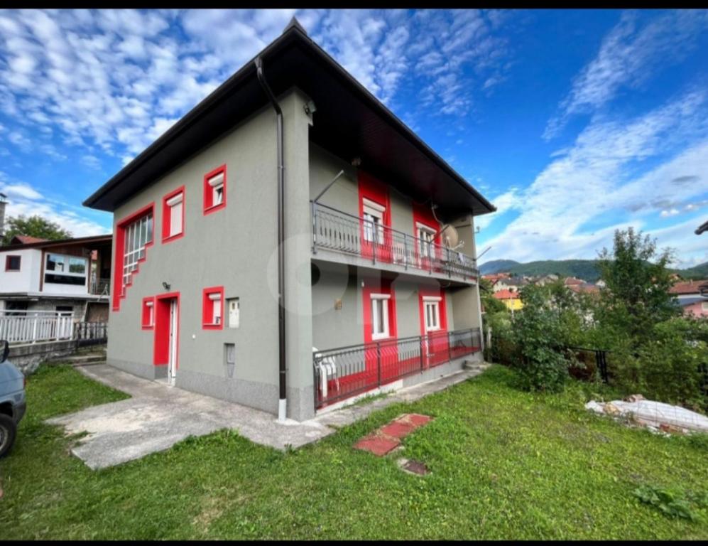 una casa con puertas rojas y un patio de césped en Apartman Dženeta, en Jajce
