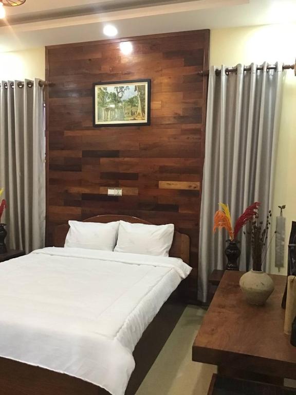 um quarto com uma cama branca e uma parede de madeira em Liza Boutique em Phumĭ Ta Phŭl