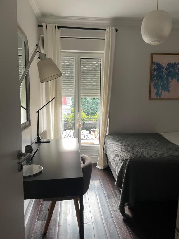 Schlafzimmer mit einem Schreibtisch, einem Bett und einem Fenster in der Unterkunft MAISON STANDING PROCHE ROLAND GARROS et JO 2024 in Boulogne-Billancourt