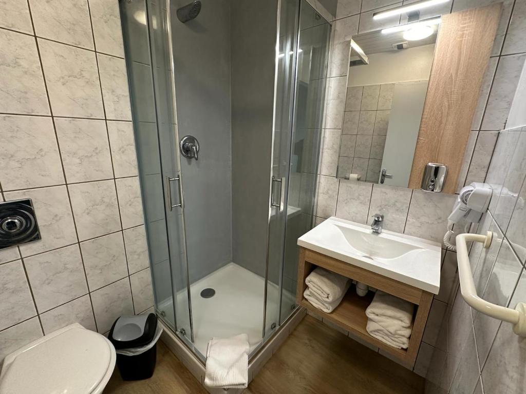 a bathroom with a shower and a toilet and a sink at Hôtel NOROTEL in Brumath