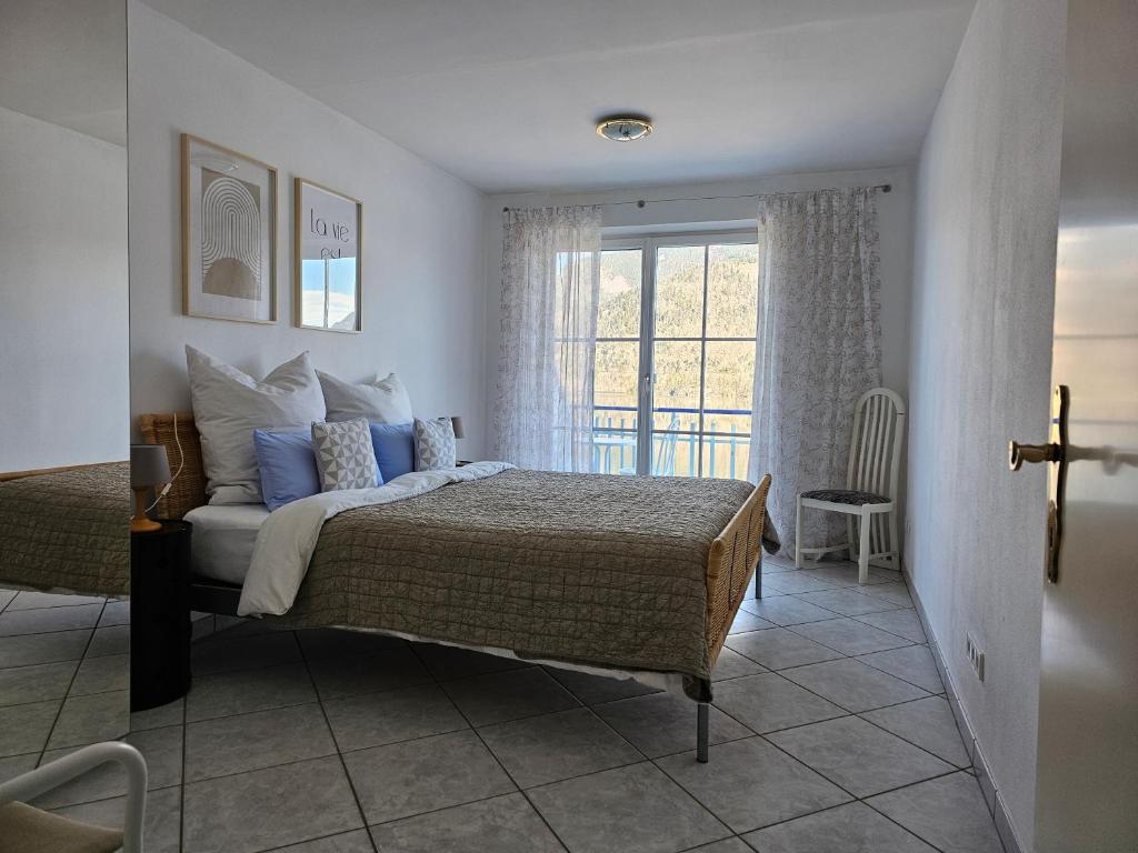 sypialnia z łóżkiem z niebieskimi poduszkami i oknem w obiekcie Lueg36 am See w mieście St. Gilgen