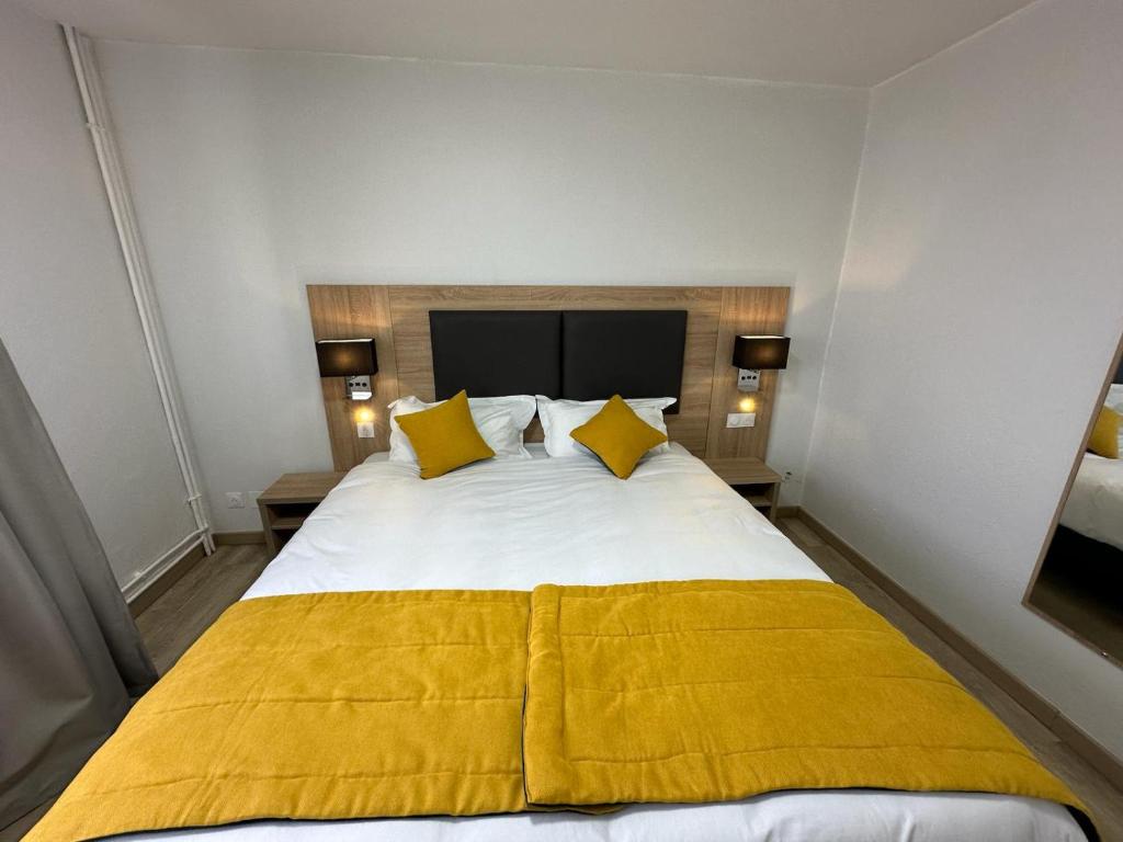 a bedroom with a large bed with yellow sheets and pillows at Hôtel NOROTEL in Brumath