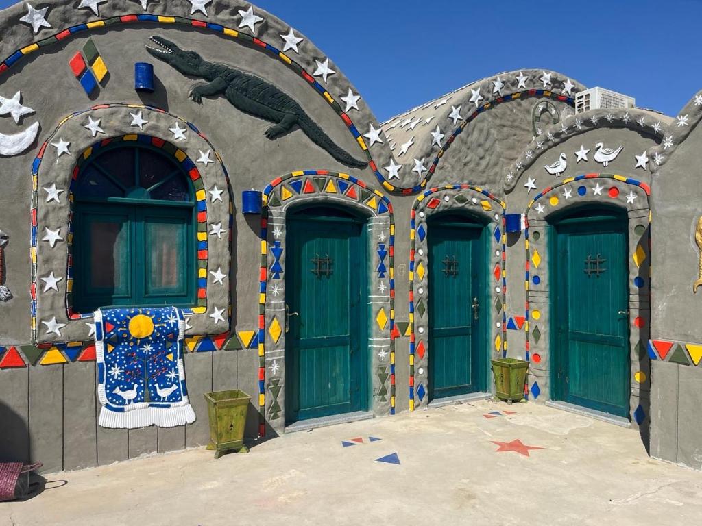 ein Gebäude mit grünen Türen und einem Gemälde darauf in der Unterkunft Anakato lodge in Al Manshīyah