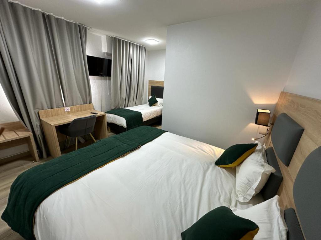 a hotel room with a large bed and a desk at Hôtel NOROTEL in Brumath
