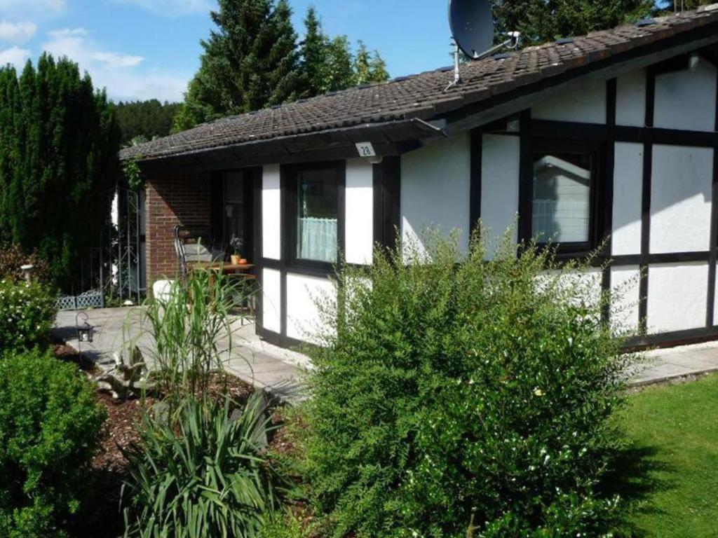 a house with black and white windows and bushes at Ferienhaus Henneseeblick - Lake - View - Terrace - Hils - Wood - WIFI in Meschede
