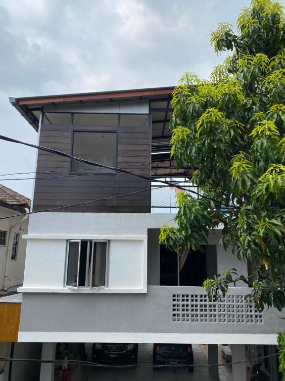 Una casa blanca con un árbol delante. en Igo homestay Subang Airport - Family Room en Shah Alam