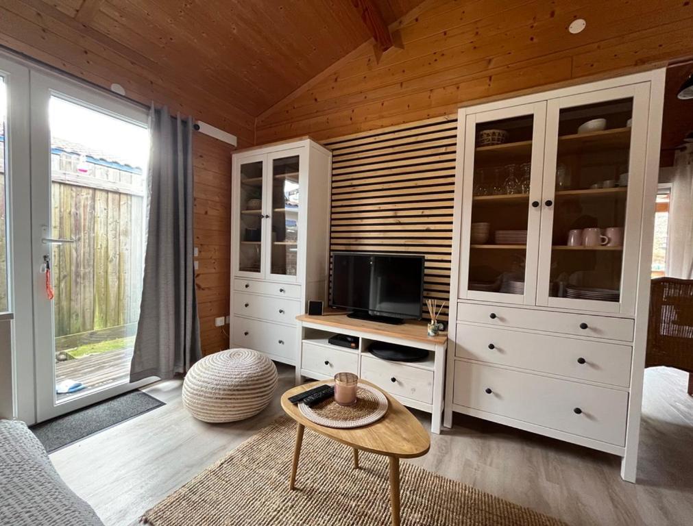 a living room with white cabinets and a tv at Chalet 6 Personnes au calme dans les landes-Mimizan in Bias