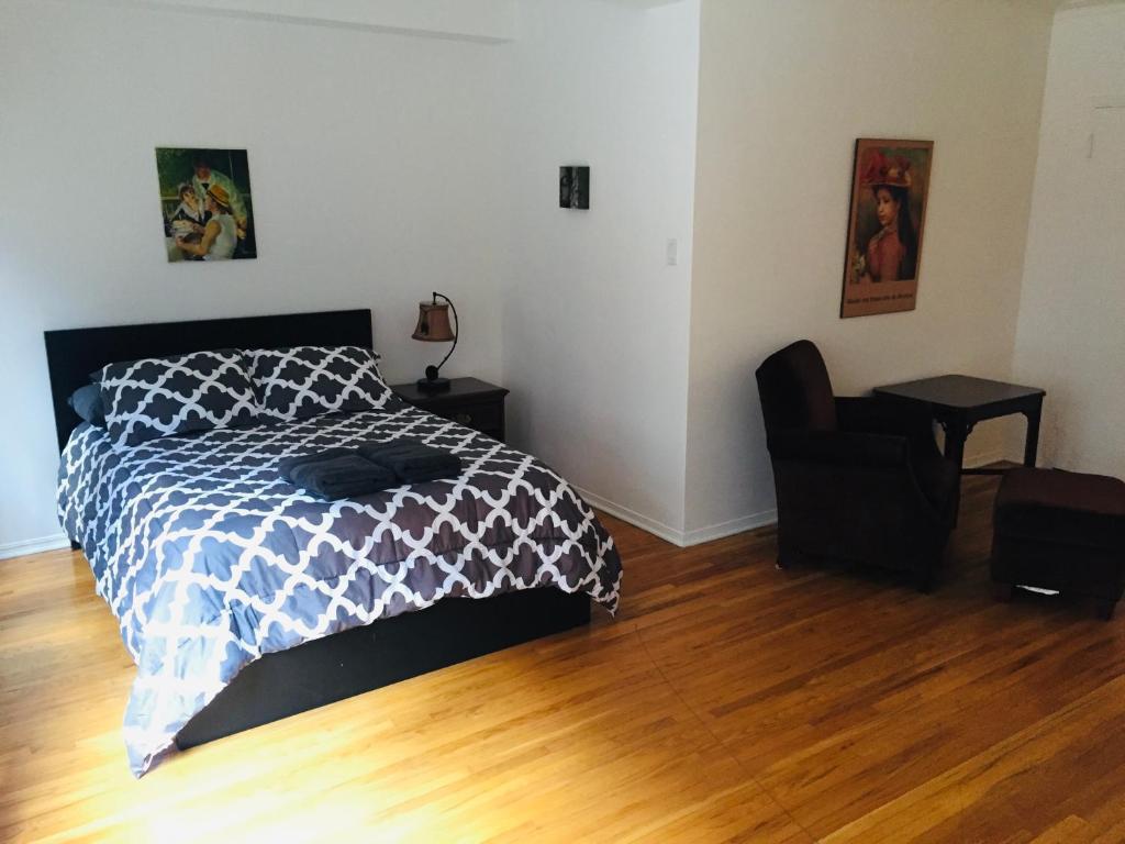 een slaapkamer met een bed en een stoel op een houten vloer bij Stylish Montreal Apartment: Comfortable Stay in the Golden Square Mile in Montreal