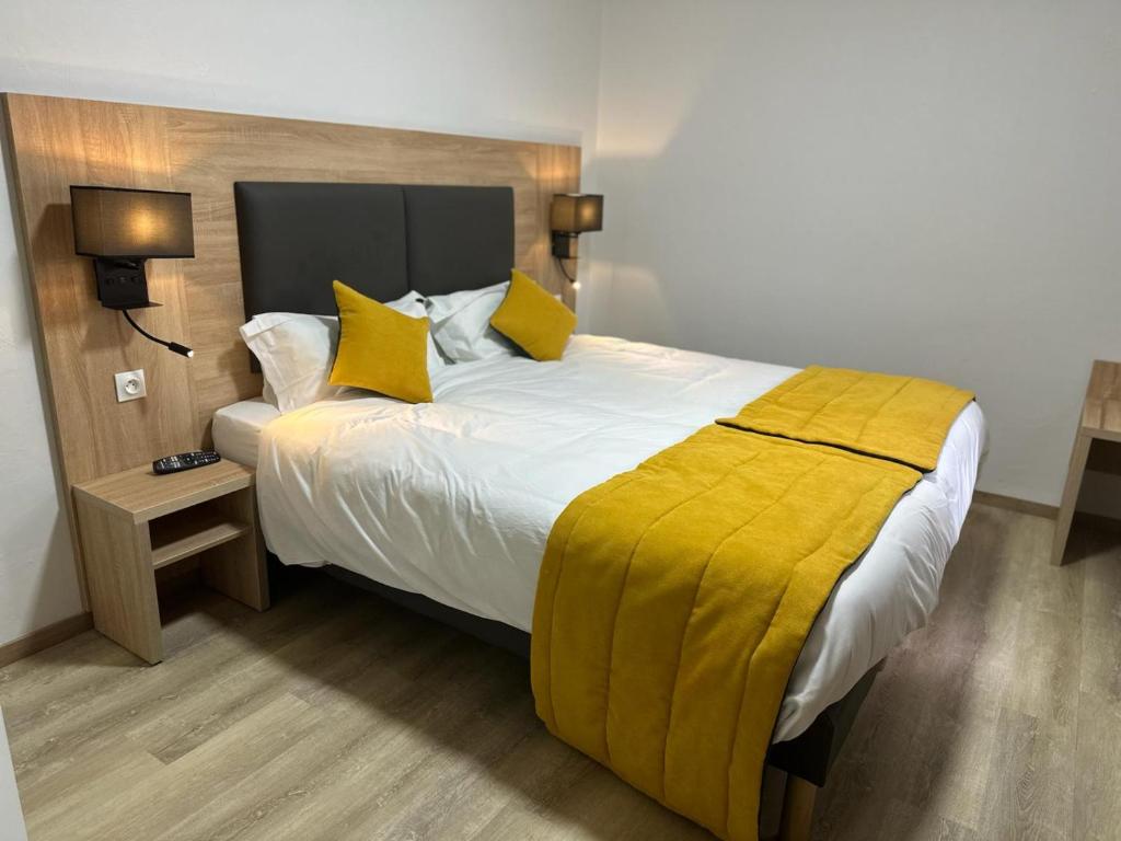a bedroom with a large bed with yellow pillows at Hôtel NOROTEL in Brumath