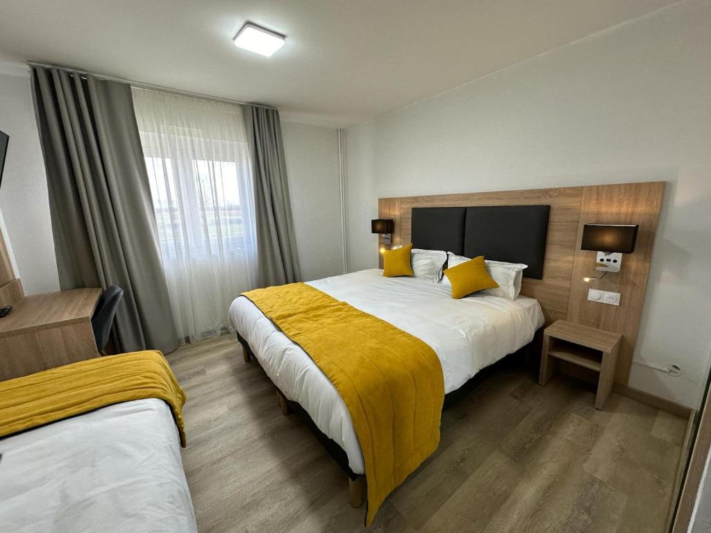 a hotel room with two beds with yellow pillows at Hôtel NOROTEL in Brumath