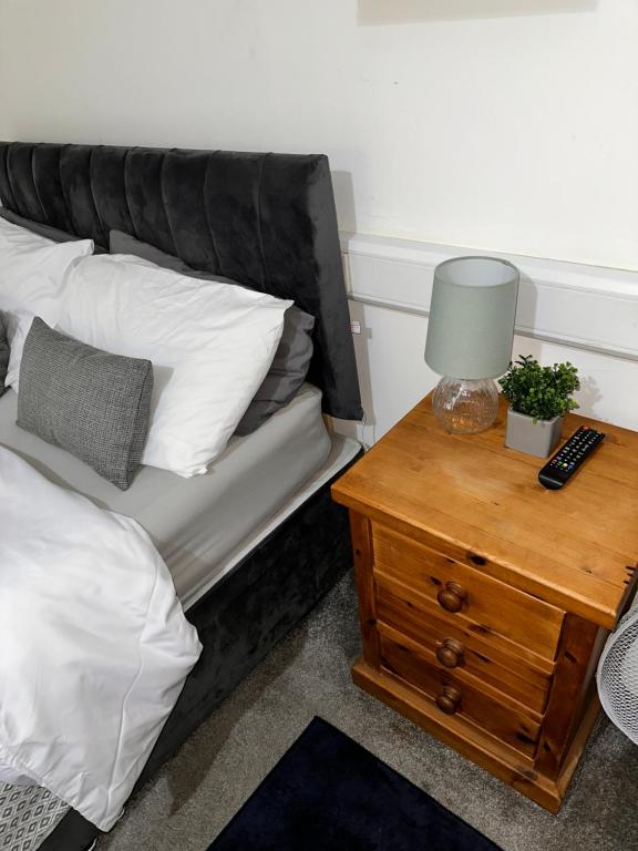a bed with a side table with a lamp on it at P&S rooms guesthouse Lincoln city centre in Lincolnshire