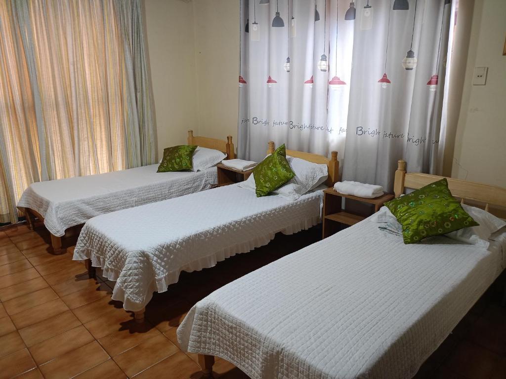 a room with three beds and a window with curtains at RESIDENCIA-UNIV in Ciudad del Este