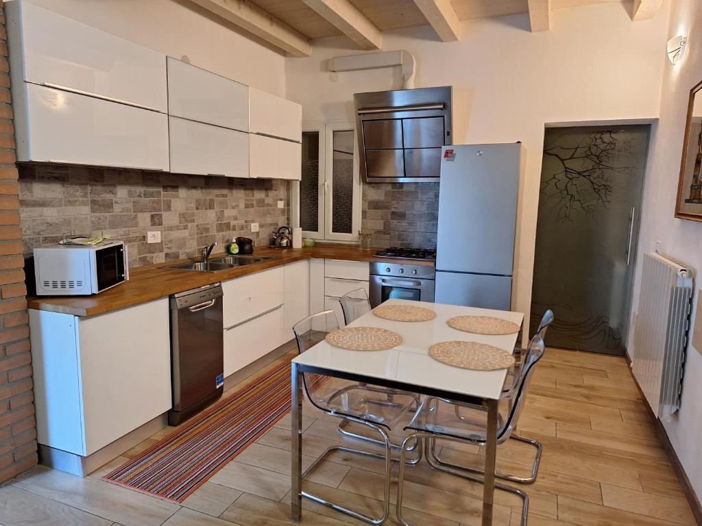 una cocina con armarios blancos y una mesa con sillas. en La Maison de André en Scaltenigo