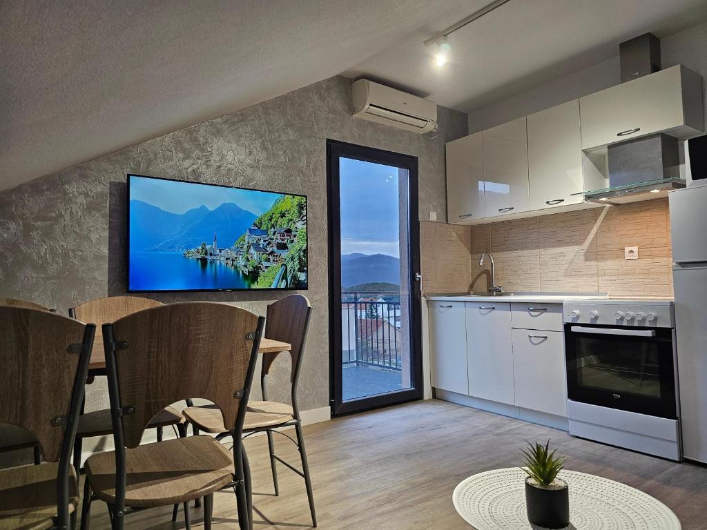 a kitchen with a table and a tv on the wall at Apartments Vraneš Tivat in Tivat