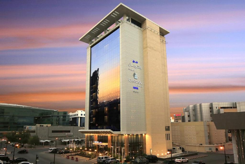um edifício alto com um grande sinal ao lado dele em Cantonal Hotel by Warwick em Riyadh
