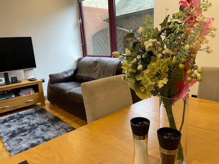 eine Vase mit Blumen auf einem Tisch im Wohnzimmer in der Unterkunft Home comfort 4 mins from Gatwick! in Horley