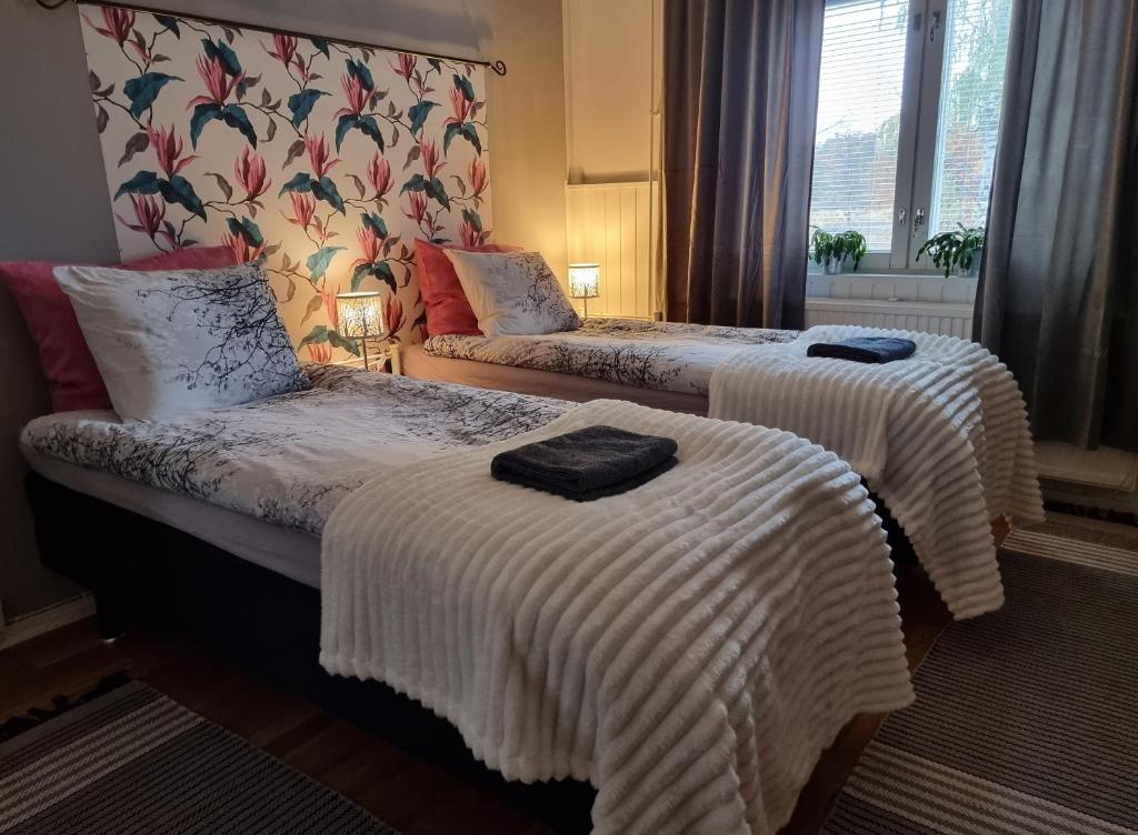 um quarto de hotel com duas camas com cobertores brancos em Wanha kunnantalo em Pudasjärvi