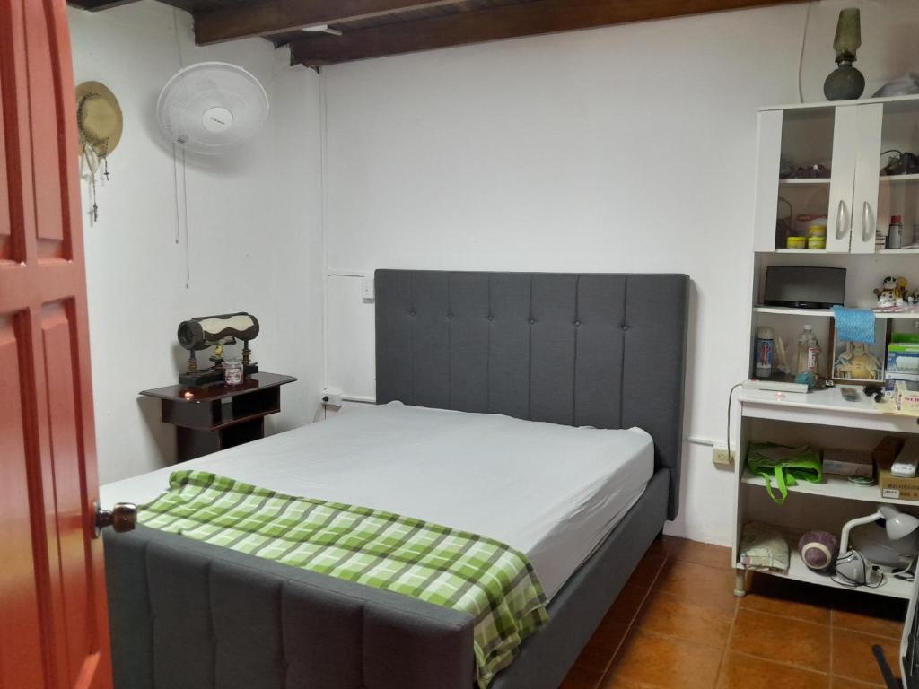Un dormitorio con una cama con una manta verde. en Cabañita Doña Tina, en Los Altos de Cerro Azul