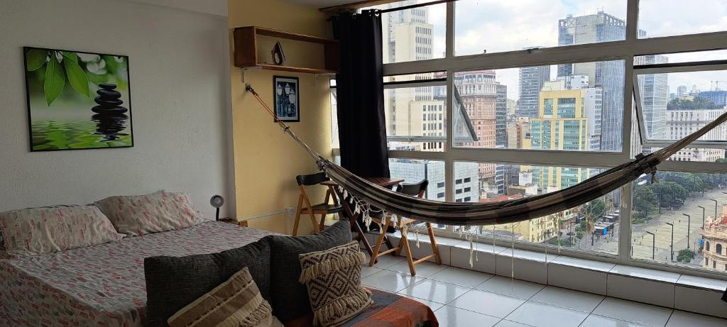 a bedroom with a hammock in front of a large window at Loft Acolhedor Vista Incrível 2719 in Sao Paulo