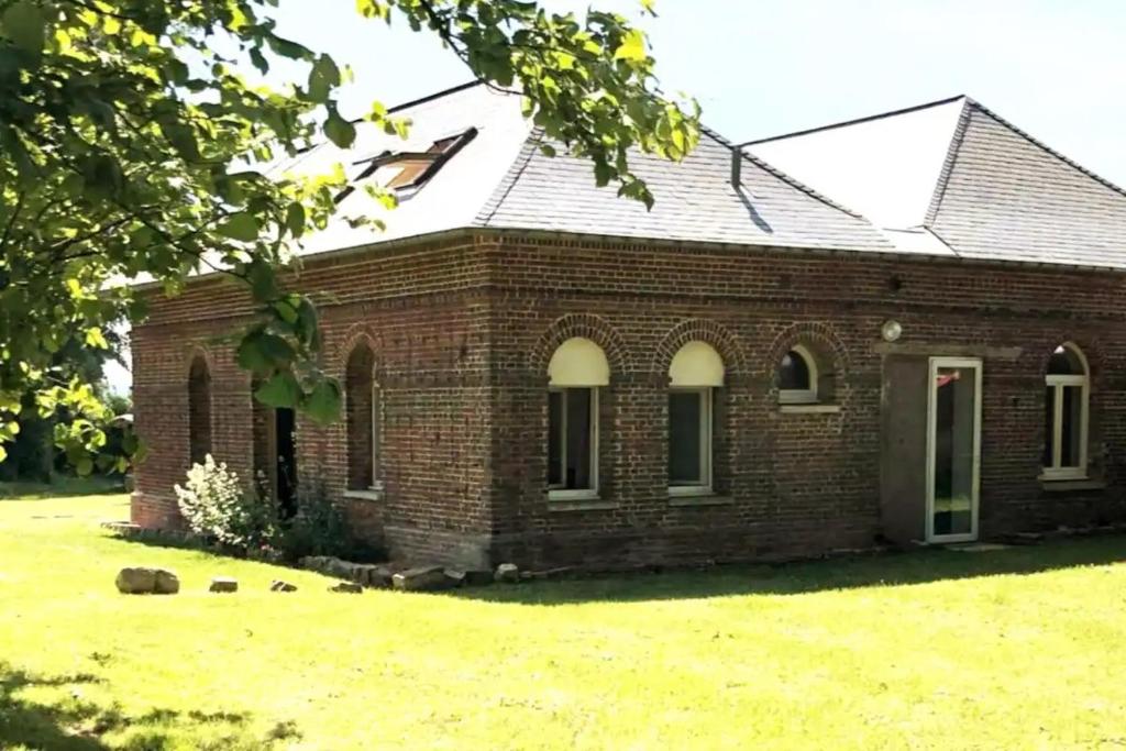 una vecchia casa di mattoni con un prato di Charmant cottage 8 personnes en Normandie a Cleuville
