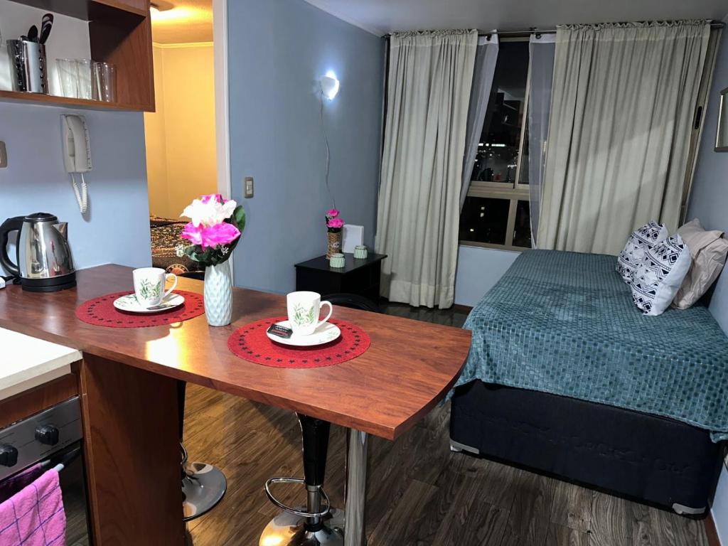um quarto com uma mesa com duas chávenas e uma cama em Amoblados santiago em Santiago