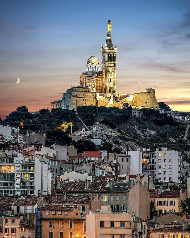 une ville avec une tour d'horloge au sommet d'une colline dans l'établissement Vieux port de Marseille, à Marseille