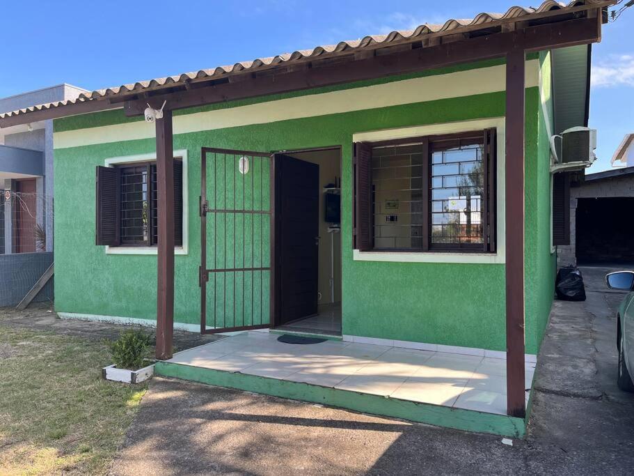 una casa verde con puerta y porche en Casa Verde en Capão da Canoa