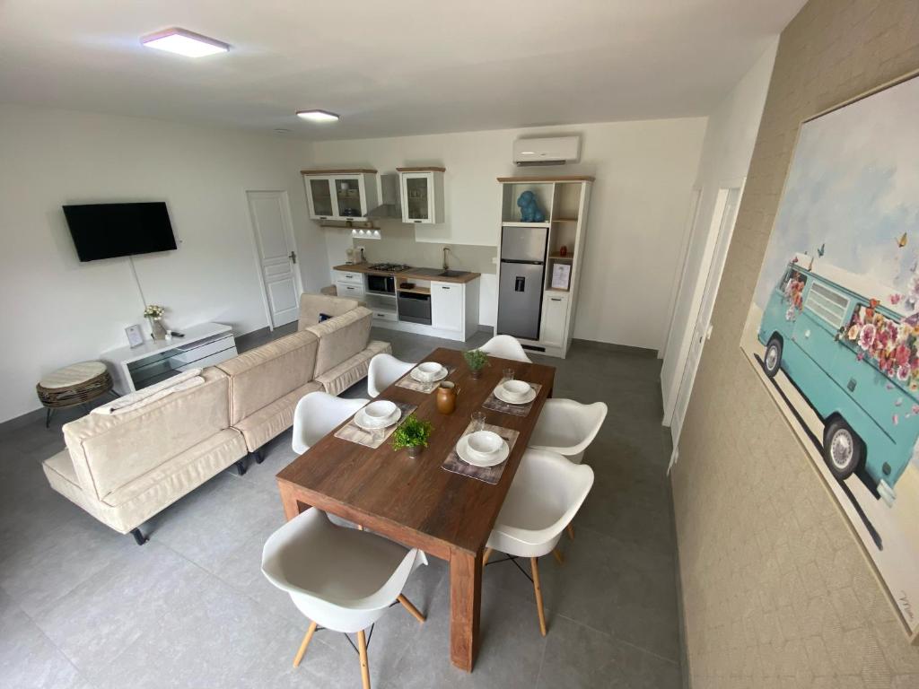 een woonkamer met een houten tafel en witte stoelen bij Logement dans propriété privée 2 in Saint Julien Les Rosiers