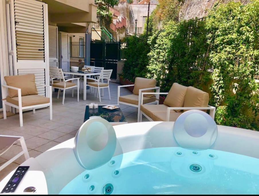 einen Whirlpool auf einer Terrasse mit Stühlen und einem Tisch in der Unterkunft CASA MANDO with Terrace and Jacuzzi in Taormina