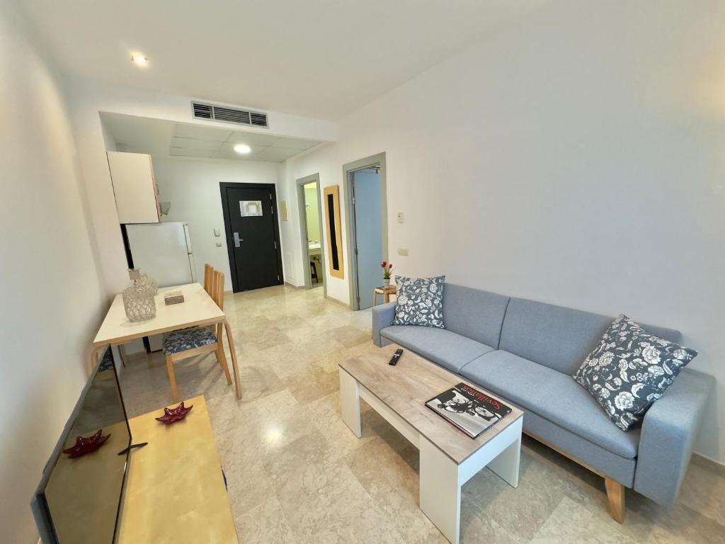 sala de estar con sofá azul y mesa en ApartSur®, en Bormujos