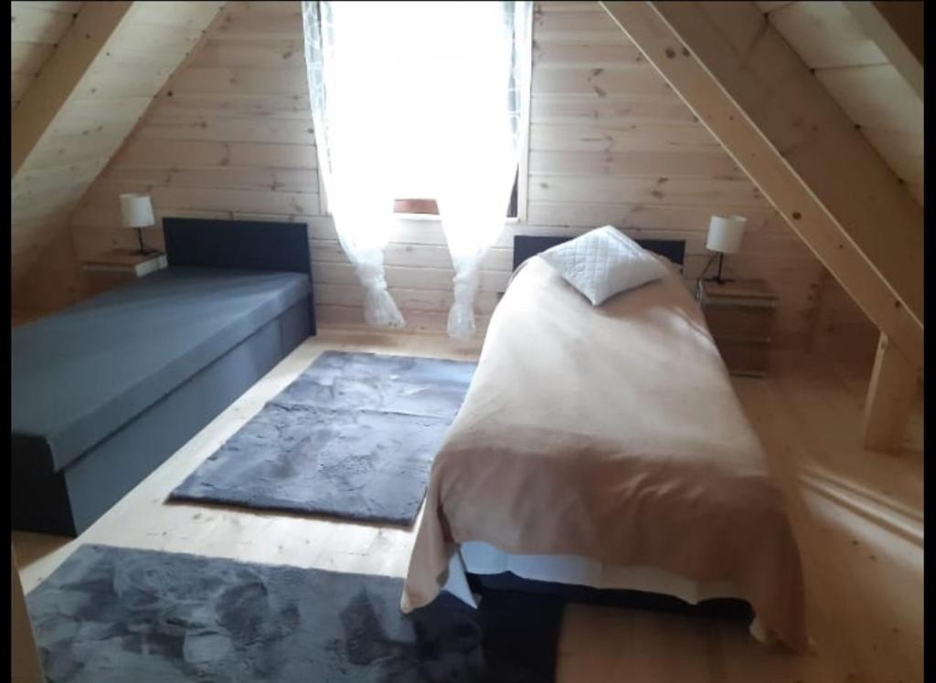 um quarto com uma cama e um sofá no sótão em Domek letniskowy Ania em Pasym