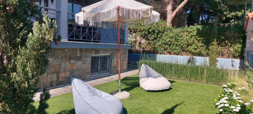 einen Garten mit zwei Kissen und einem Sonnenschirm in der Unterkunft Augoustinos - Sea Side Luxury Apartments in Artemida