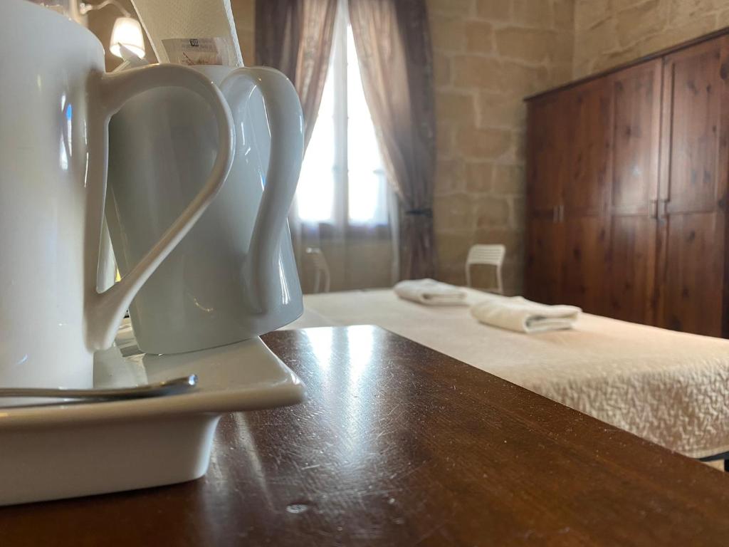 a white pitcher on a table next to a bed at Xemx in Qala