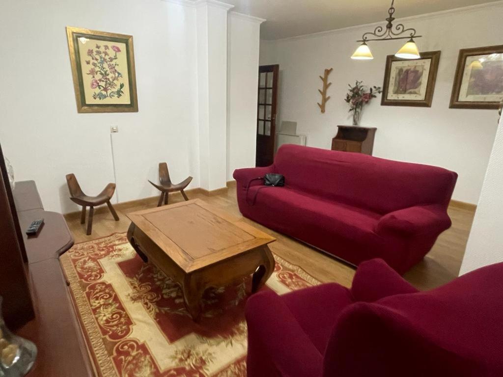 een woonkamer met een rode bank en een salontafel bij Piso O cruceiro in O Grove