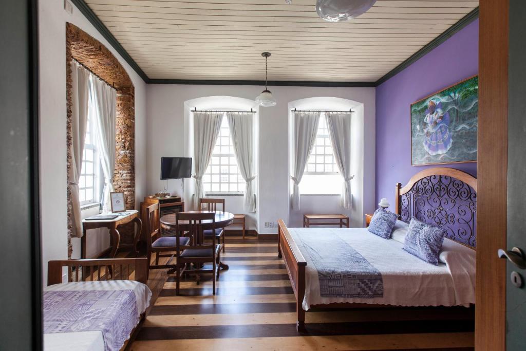 a bedroom with two beds and a table and chairs at Pousada Solar dos Deuses in Salvador