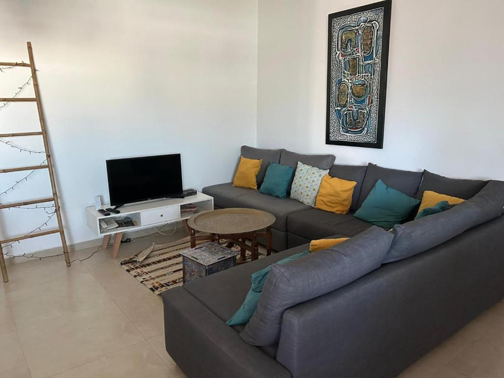 sala de estar con sofá y TV en Les Portes de l'Océan avec piscine accessible l'été et sans plan sécheresse en El Harhoura