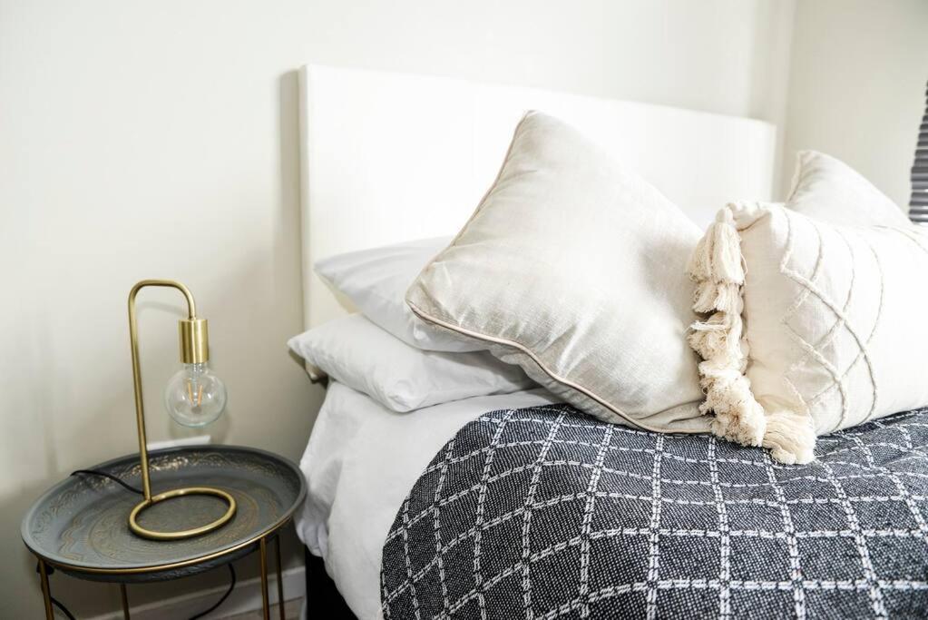 um quarto com uma cama com almofadas brancas e uma mesa em Cozy Hidden gem in Midrand em Midrand