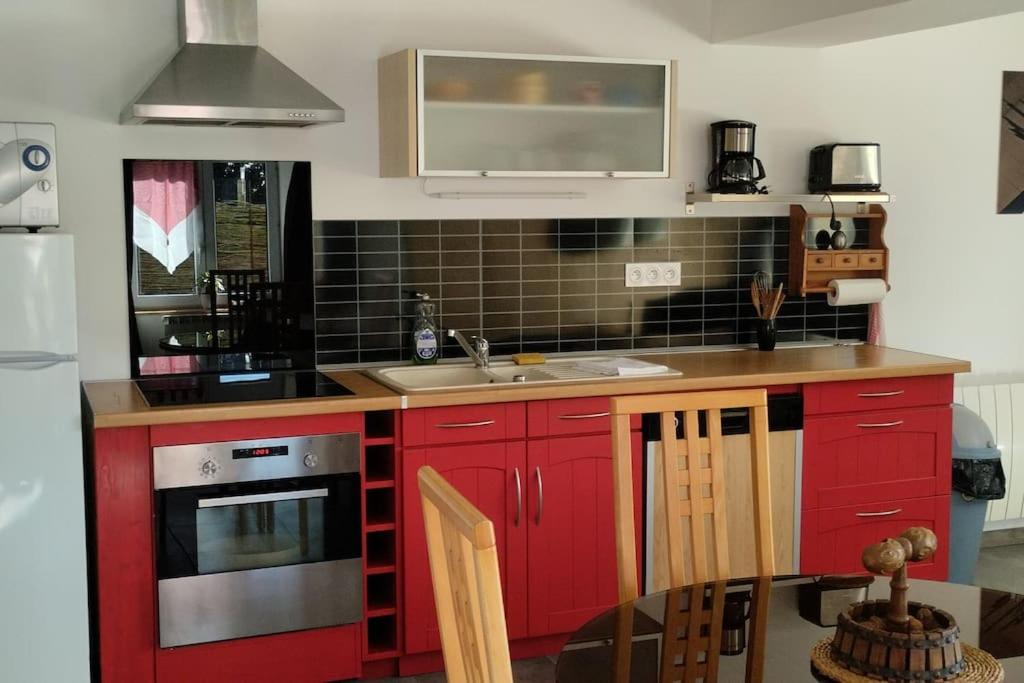 a kitchen with red cabinets and a sink at Gite de la longue fosse in Mandeville-en-Bessin