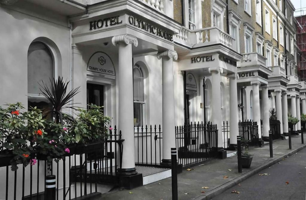a white building with columns and a fence at Olympic House Hotel in London