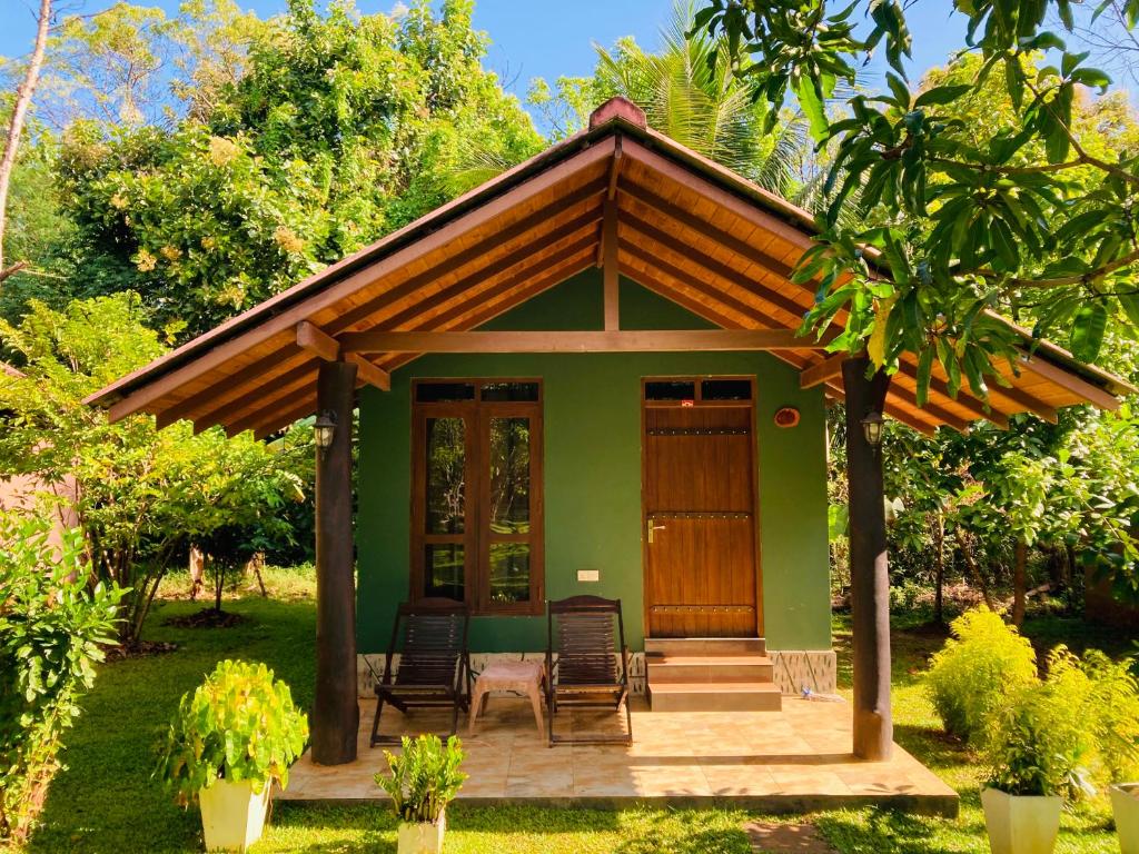mały zielony dom z krzesłami i werandą w obiekcie suncity privacy cottages w mieście Udawalawe