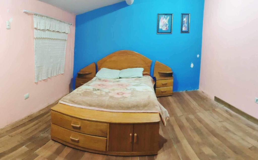 een slaapkamer met een bed en een blauwe muur bij LA CASA DEL ABUELO in Urubamba