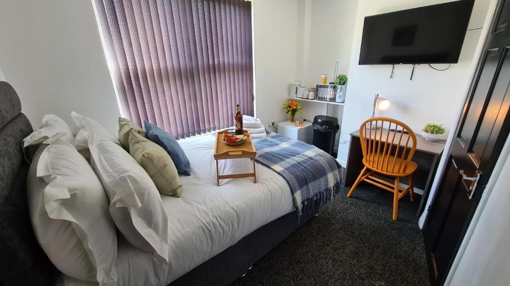 een slaapkamer met een bed, een bureau en een televisie bij Moorfield House in Banbury