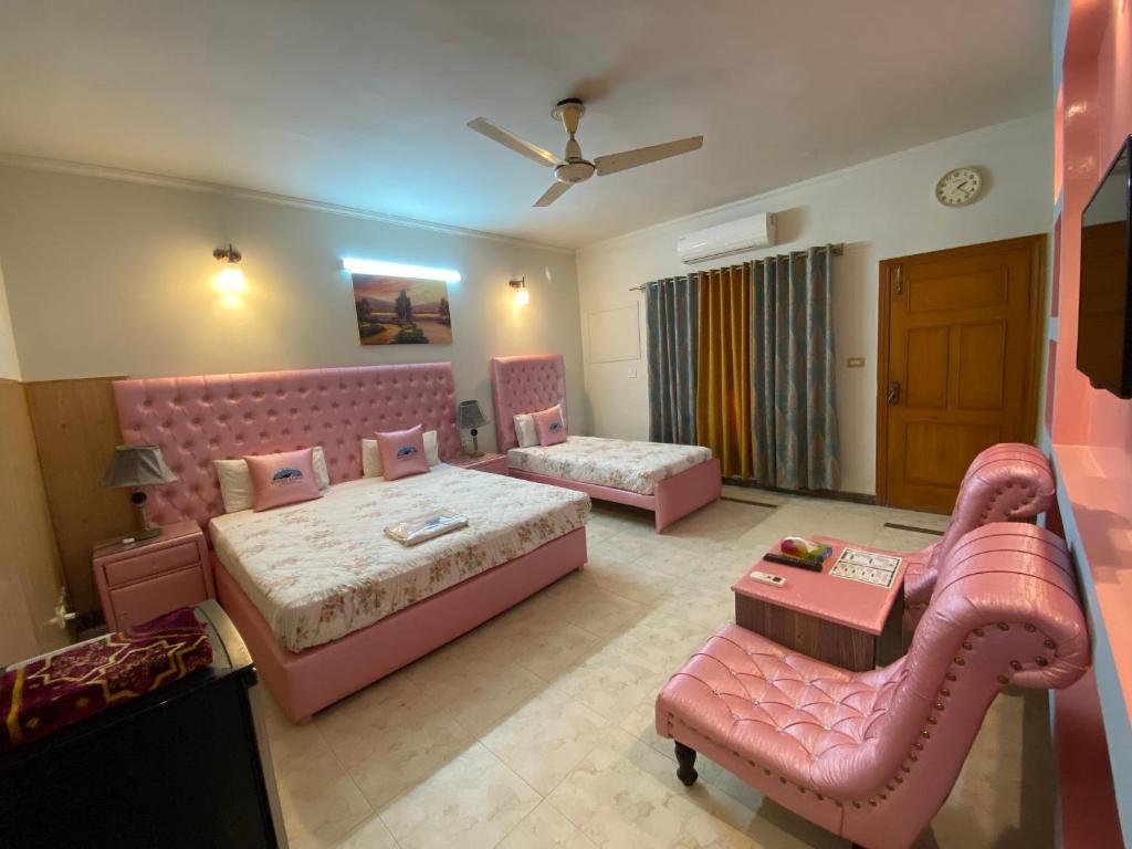 um quarto amplo com 2 camas e um sofá em Fusion Lodge em Islamabad