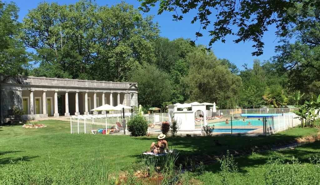 un grupo de personas sentadas en la hierba junto a una piscina en Camping Parc d'Audinac Les Bains en Saint-Girons