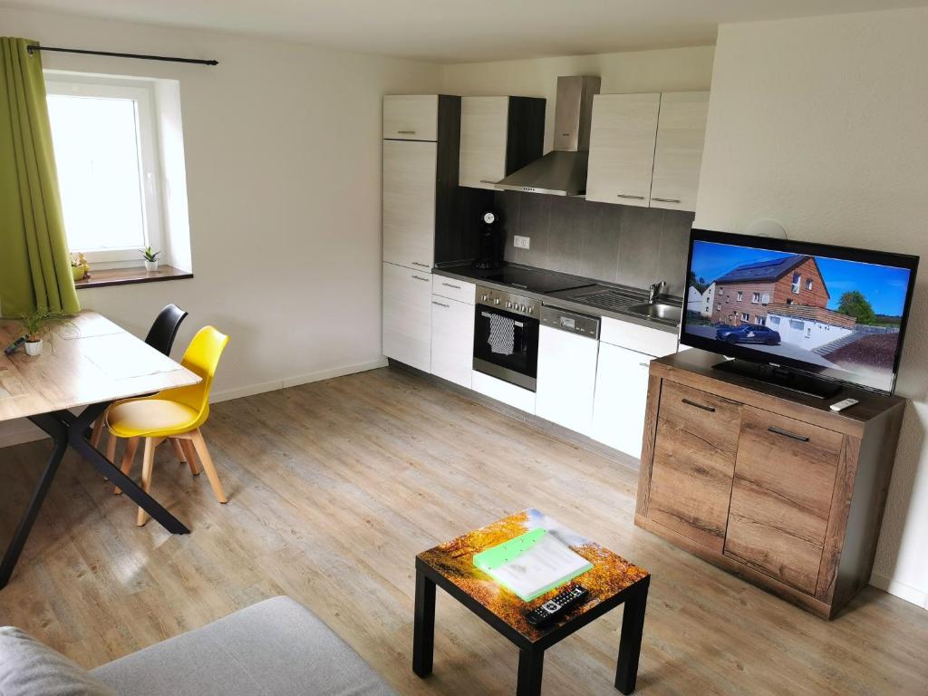 a living room with a kitchen with a tv and a table at Speedys Apartments am Brünnchen in Herresbach