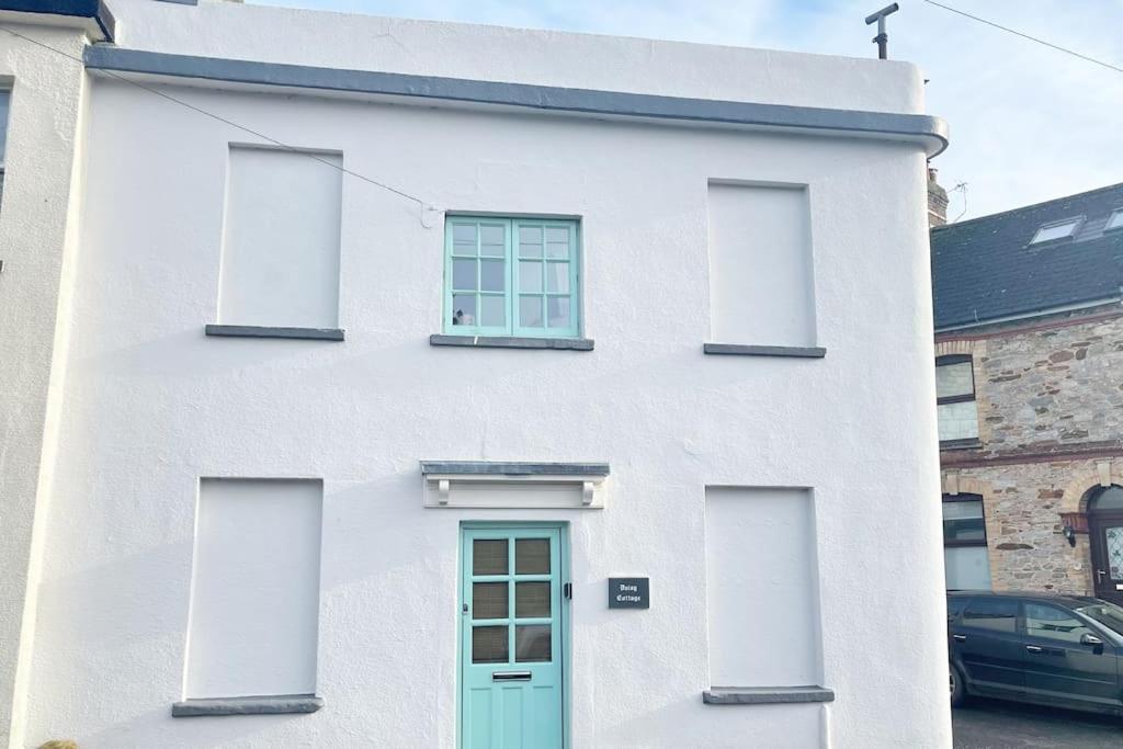 a white house with a green door and windows at A charming cottage set in Bridgetown Totnes. in Dean