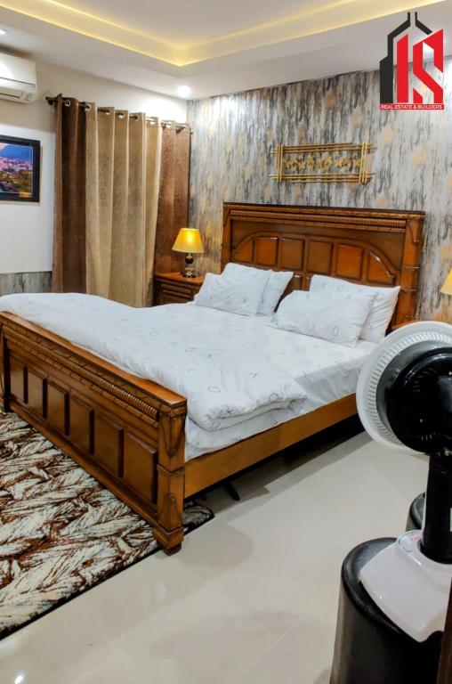 a bedroom with a large wooden bed with white sheets at Sweet Retreat Loft in Rawalpindi