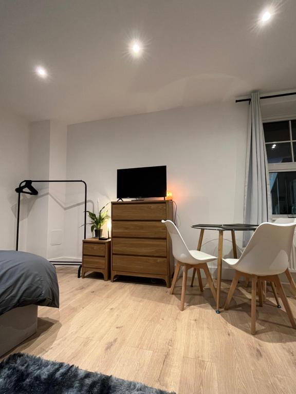 um quarto com uma mesa, uma televisão e uma cama em Cosy Maidstone Flat near Station (Town Centre) em Kent