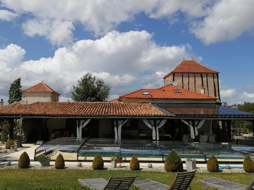 a building with a tile roof with chairs in a yard at Gîte Rozies Dunes 6 p in Dunes